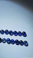 Two rows of natural blue sapphire round cabochons with strong blue color; stones appear translucent to transparent with smooth cabochon cut surfaces.