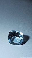 Clear photo of the natural sky blue topaz gemstone showing cushion cut, facets, and sky blue color under light.