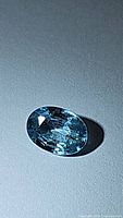 Close-up photo of a natural lagoon blue zircon oval cut gemstone showing transparent and bright blue facets with good clarity.