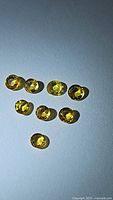 Photo showing eight round cut natural canary yellow sapphires arranged on white background with bright yellow coloration visible.