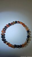 Photo of natural dream agate bracelet showing round multi-colored beads arranged in a circular stretchy design.