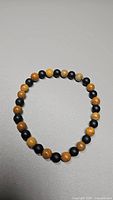 Top view of the natural wood jasper and matte jet black onyx bead stretchy bracelet showing bead colors and sizing