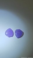 Photo showing matching pair of lavender jade gemstones, fancy spade cut, polished and translucent.