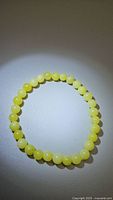Top view of a stretchy bracelet made of round natural lemon jade beads, pale yellow color, uniformly sized