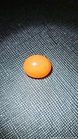 Close-up image of an oval orange cabochon gemstone on textured black background showing smooth surface and bright mandarin color.