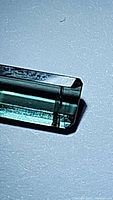 Close up photo showing the baguette cut tourmaline with blue-green Paraiba color and facets under light.
