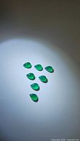 Seven vivid green onyx pear cabochons arranged with some spread out