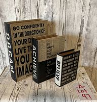 Set of three book style storage boxes arranged standing upright showing front and spine text