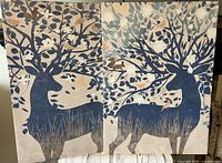 Photo of two canvas wall art pieces placed side by side showing blue deer silhouettes with tree branch antlers and woodland animals in a nature-themed design.