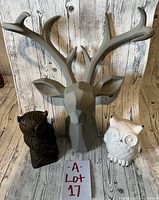 Lot of three animal decor pieces including gray ceramic deer head wall hanging, white ceramic owl figurine, and dark wood owl figurine.
