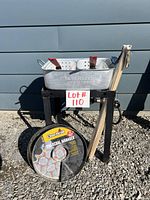 Full view of the propane burner setup with rectangular pan, frying baskets, charcoal flavor pans, and bundle of wooden skewers on black metal frame with wheels.