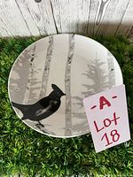 Plate showing black bird in front of gray tree trunks design, round with 9.5 inch diameter.
