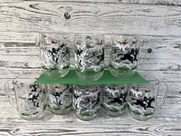 Eight Hazel Atlas Fox Hunt beer mugs arranged with three on a raised green platform and five below, showing detailed hunting scenes on clear glass.