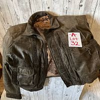 Front view of vintage brown leather Indian motorcycle jacket with multiple pockets and collar, laid flat on wooden surface.