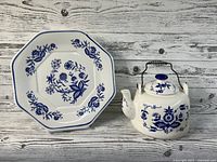Teapot and serving plate together showing blue onion pattern and metal handle on teapot