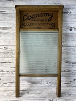Front view of vintage Economy Canadian Woodenware Co. washboard with wooden frame and textured glass surface, with branding on top panel.