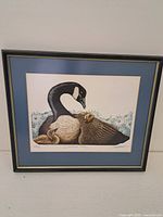 Full view of the framed 'Canadian Family' print showing the goose family artwork with a blue mat and black frame with gold edge.