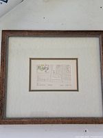 Full view of framed etching showing the artwork and wooden frame with mats.