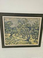Framed print showing olive trees in swirling impressionist style with dark wooden frame.