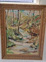 Full front view of the gilt-framed oil painting showing a landscape forest scene with a stream and trees.