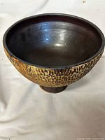 Side angle view showing the textured brown and black exterior surface and the black smooth glazed interior of the vase.