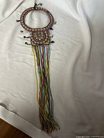 Full view of the large African necklace showing its circular collar, rectangular pendant, and long dangling bead strands