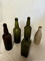 Five bottles on white background: two slender green Phoenix Brewery, one rectangular S.G. Myers, one amber Victoria Brewing, one stoneware