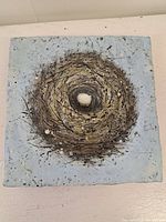 Top view of the 4x4 inch art panel showing nest-like textured artwork with blue background and central white element (egg-like).