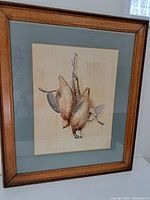 Overall framed watercolour painting showing two hanging game birds.