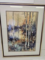 Full front view of the framed watercolour painting depicting birch trees in autumnal colors under glass.