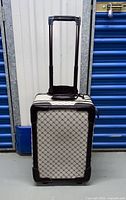 Front view of Ralph Lauren suitcase with extended telescoping handle, standing vertically.