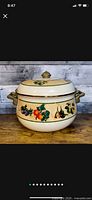 Front view of vintage stock pot showing vegetable decoration and one handle