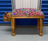 Side profile of the wooden elephant foot stool showing wood carving and colorful cushion
