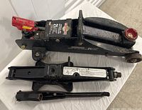 Two black hydraulic car jacks shown side by side on a white surface.