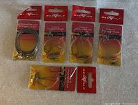 Photo showing 5 new Redwolf fishing accessories in factory packaging: one stainless steel fishing ladder and four pickerel rings with hooks and orange bead details.