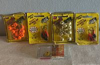 Five Jim's Fancy Wobbler Jigs in factory packaging showing various colors including orange, red, and white, displayed side by side on a surface.