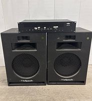 Front view: Biamp Systems MXA150 rack-mount amplifier placed on top of two Klipsch speakers.