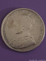 Close-up photo of obverse side of the coin showing King George V crowned portrait with surrounding inscription.