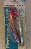 Front view of factory packaged Bomber Badonk-a-Donk fishing lure showing color and hooks
