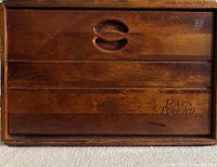 Front view of the wooden bread box showing the roll-top lid with carved handle and 'Pain Bread' text.