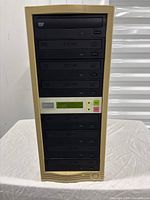 Front view of the beige 7 drive duplicator tower showing 7 DVD/CD drives and control panel.