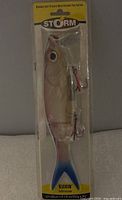 Front view of one Storm Kickin Minnow lure in factory packaging showing realistic fish design, two treble hooks, yellow label with brand name and lure size details.