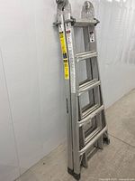 Ladder folded in A-frame position against wall