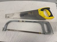 Duramax Pro hand saw and metal frame hacksaw on white fabric background