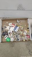 Box with a collection of vintage collectible pins in various conditions and packaging.