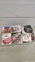 A plastic container filled with various rectangular and square cardboard beer coasters showing diverse brand logos and styles.