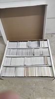 Box filled with multiple rows of white-backed hockey trading cards divided by cardboard sections.