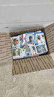 Top view of a cardboard box filled with a mixed collection of baseball cards showing multiple players and card designs.