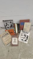 Overview photo of vintage books and booklets on magic and illusion, arranged on the floor showing front covers of some titles related to Houdini, hypnotism, and magic tips.
