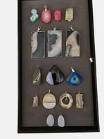 Full lot of 16 assorted agate druzy pendants arranged on tray showing colors and variety